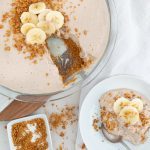 banana cheesecake with one slice on the side with a white background