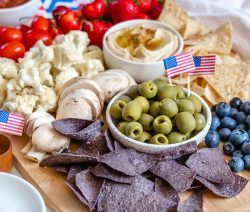 colorful charcuterie board with chips, olives and tomatoes