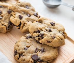 four chocolate chip cookies on a brown tray with a white background