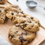 four chocolate chip cookies on a brown tray with a white background