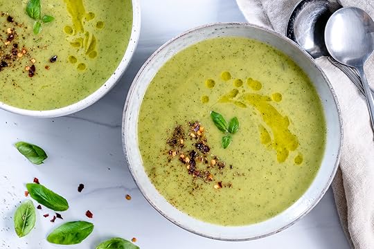two white bowls of zucchini basil soup in a white background