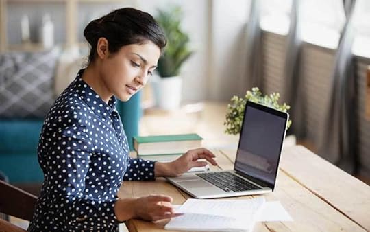 woman at desk writing with a laptop computer