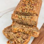 A loaf of zucchini bread sliced on a white cutting board