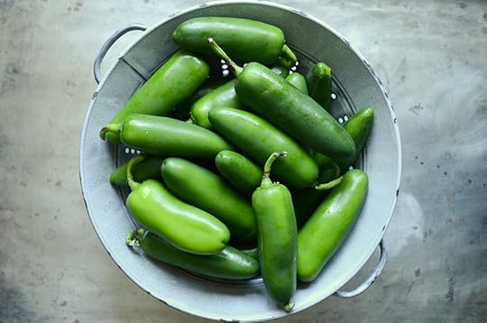 An enameled colander filled with three pounds of fresh jalapeno peppers, resting on an old sheet pan.