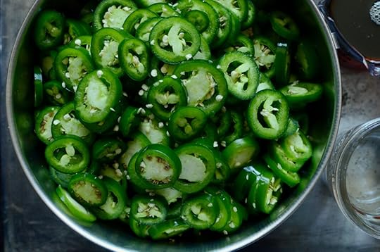 A close up shot of a metal bowl filled with sliced jalapeno peppers.
