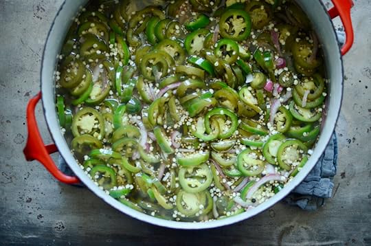 A red enameled pot filled with the cooked pickles. You see the sliced jalapeno rounds interspersed with slivers of red onion.