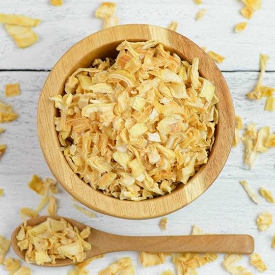 Overhead photo of a small wooden bowl and spoon filled with dehydrated onion flakes.