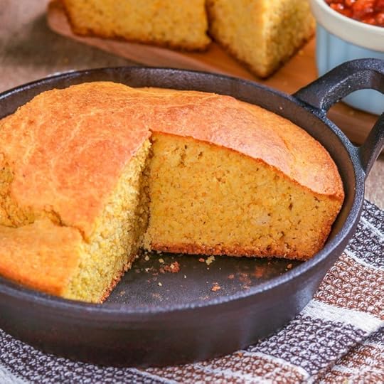 A big hunk of cornbread in a cast-iron skillet.
