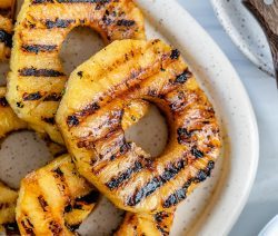sliced grilled pineapples on a white tray in a white background