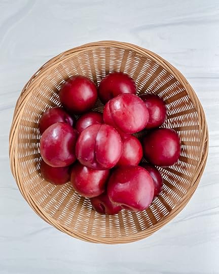 plums in a basket in a white background