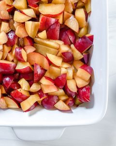 cut plums in white container in white background