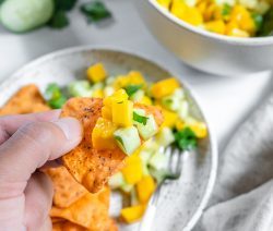 two white bowls with mango cucumber salsa in a white background