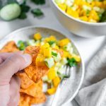 two white bowls with mango cucumber salsa in a white background