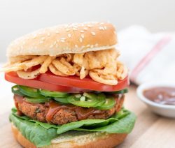 spicy red bean burger on a wooden surface with a sauce in a small white bowl in the background