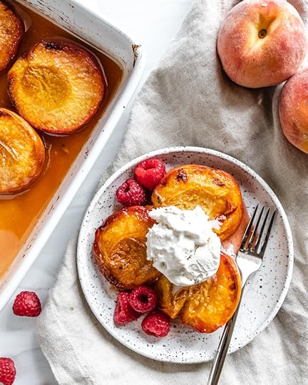 roasted peaches with raspberries topped ice cream with a white background