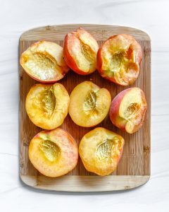 halved peaches on cutting board with white background