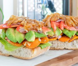 two sweet potato and avocado sandwiches on cutting board