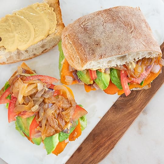 two sweet potato and avocado sandwiches on cutting board