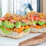 two sweet potato and avocado sandwiches on cutting board