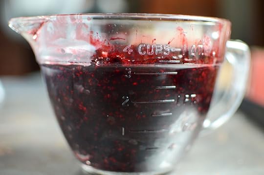Three and a half cups of mashed black raspberries in a vintage glass measuring cup.