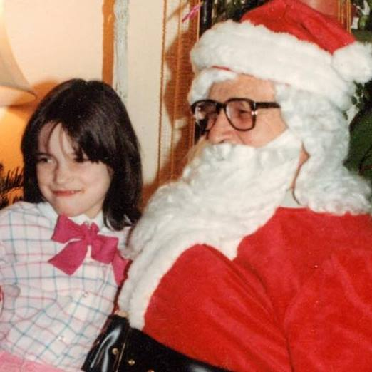 10 year old brunette girl with pink shirt sitting on Santa's lap