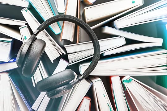 Wireless overhead black headphones lie on a bunch of books.