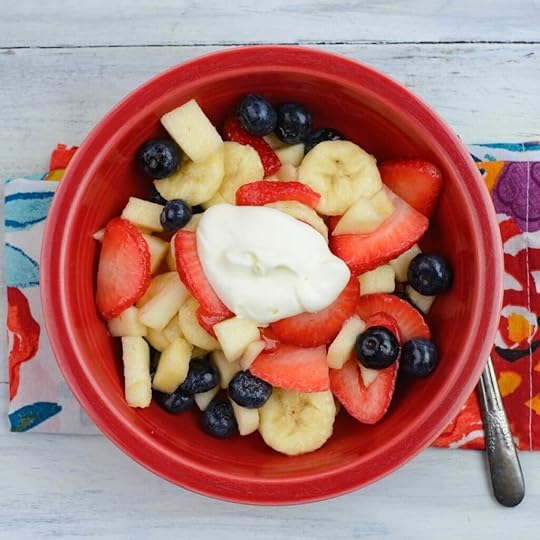 Fruit salad with crème fraiche in a red bowl.