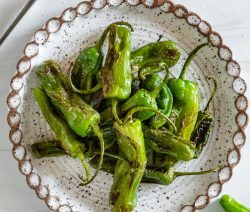 shishito peppers blistered and charred on plate on white surface