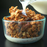 pouring milk into a bowl of gluten free granola.