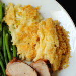 closeup of cheesy hashbrown casserole on a dinner plate.