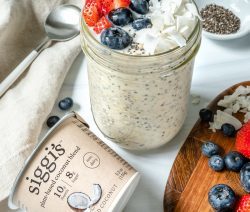 overnight oats in glass jar with fruit on top in a white background