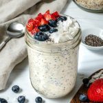 overnight oats in glass jar with fruit on top in a white background
