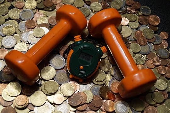 A set orange dumbbells and a stopwatch on a pile of coins.