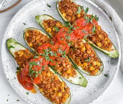 4 tex mex zucchini boats on white plate with white background