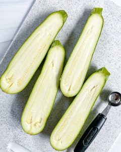 cut zucchinis sliced in half on white cutting board