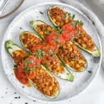 4 tex mex zucchini boats on white plate with white background