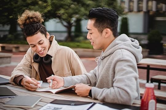 two guys are writing in their notebooks