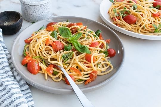 plate of tomato basil pasta with a blue and white kitchen towel