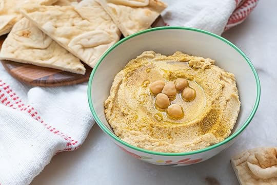 bowl of hummus with crackers on the side in a white background
