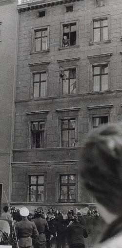 A man tosses a child out a 4th story window to escape the Berlin Wall.