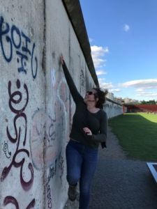 Young woman measuring the height of the Berlin Wall