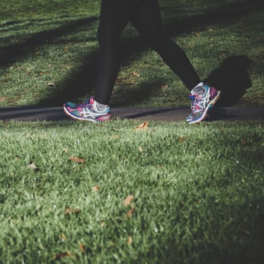 A person walking in sneakers on a sidewalk.