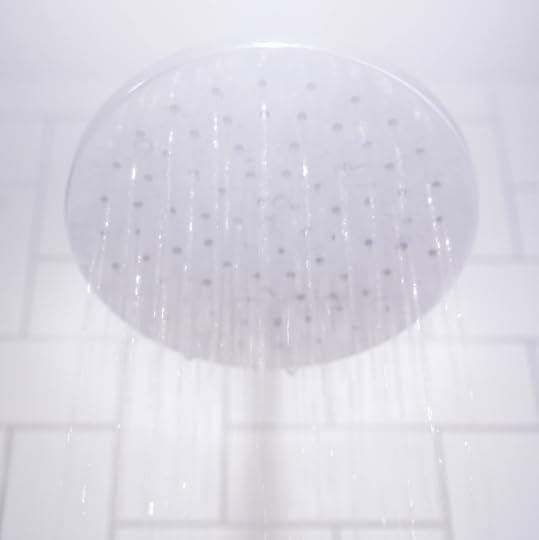 A shower head with water streaming from it.