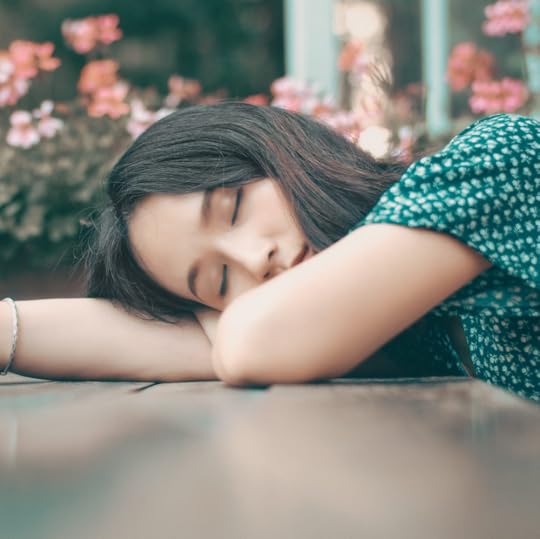 A young woman sleeps with her upper body resting across her desk.