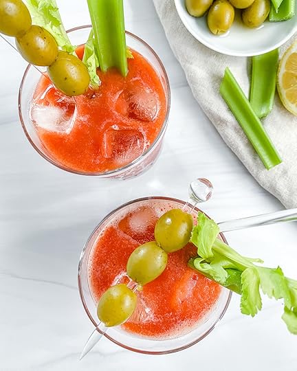 2 Virgin Bloody Mary drinks in glass with decorative olives and veggies in the cup and on the side with a white background