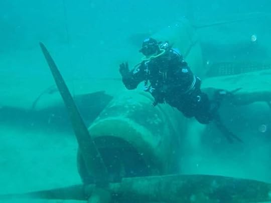 Scuba diver waves at camera net to the propellor of a submerged airplane at Dutch Springs, Pennsylvania