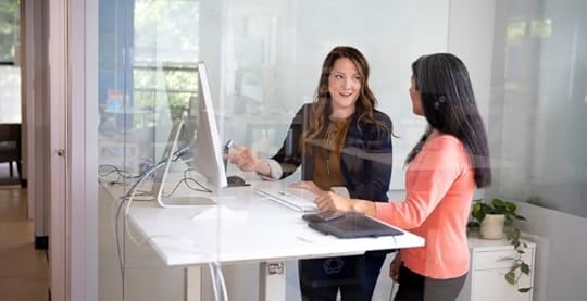 Two women talking in office next to desk