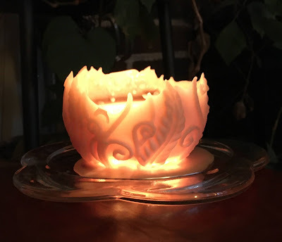 Yellow beeswax candle, spherical, with vine-like designs on the outside.