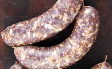 Three venison bratwurst on a cutting board