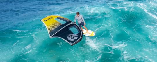 Drone shot of wing foiler on a yellow board with yellow and black sail